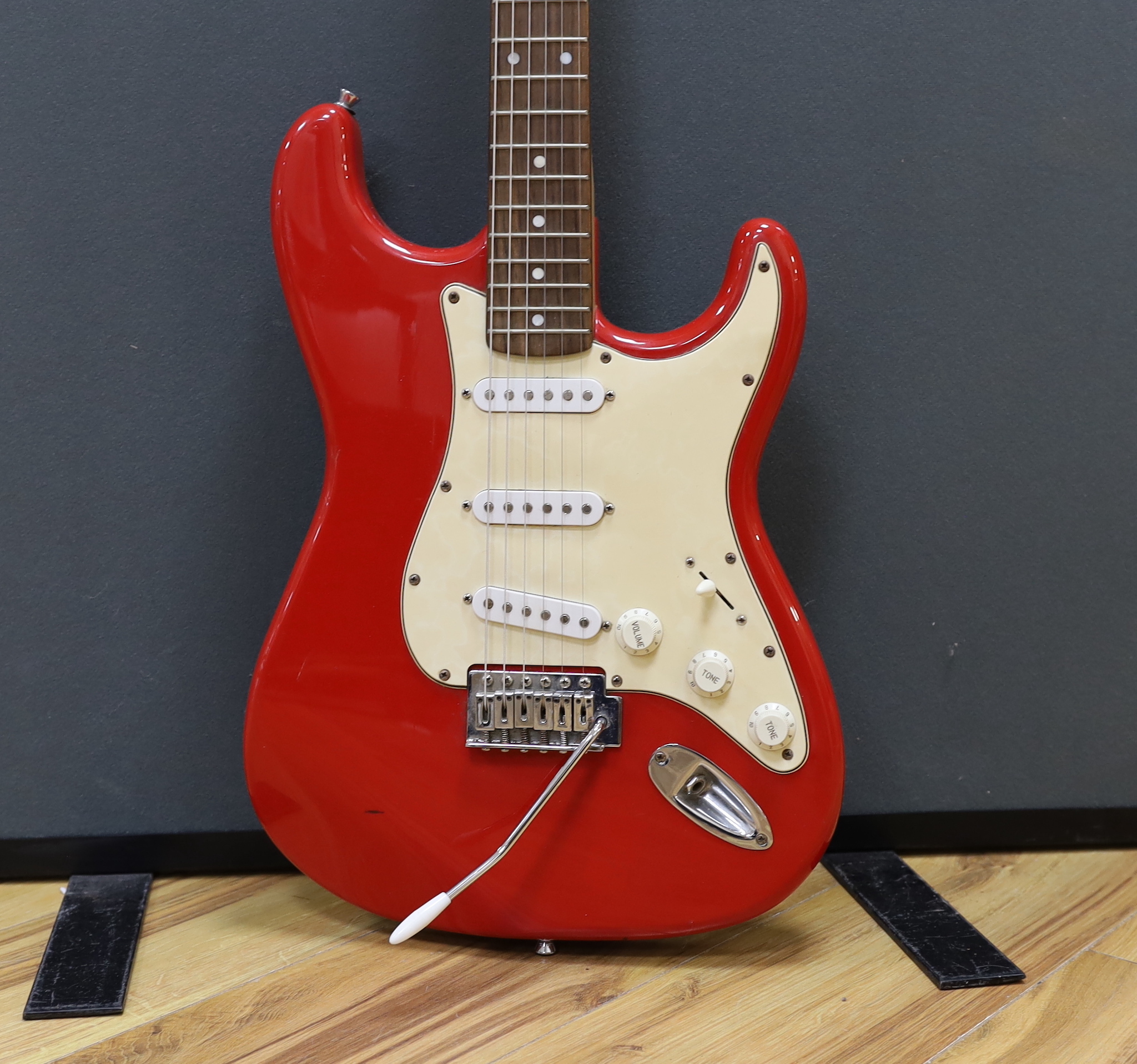 A Squier Strat by Fender electric guitar with rosewood neck and red lacquer body